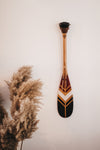 Pagaie décorative en bois de petite taille. Fixé avec une attache en cuir de vache huilé Onquata.