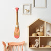 Pagaie décorative de petite taille (24 pouces). Pagaie en bois de trois couleurs fixée à un mur blanc. Munie d'un lacet en cuir décoratif – Onquata à Wendake